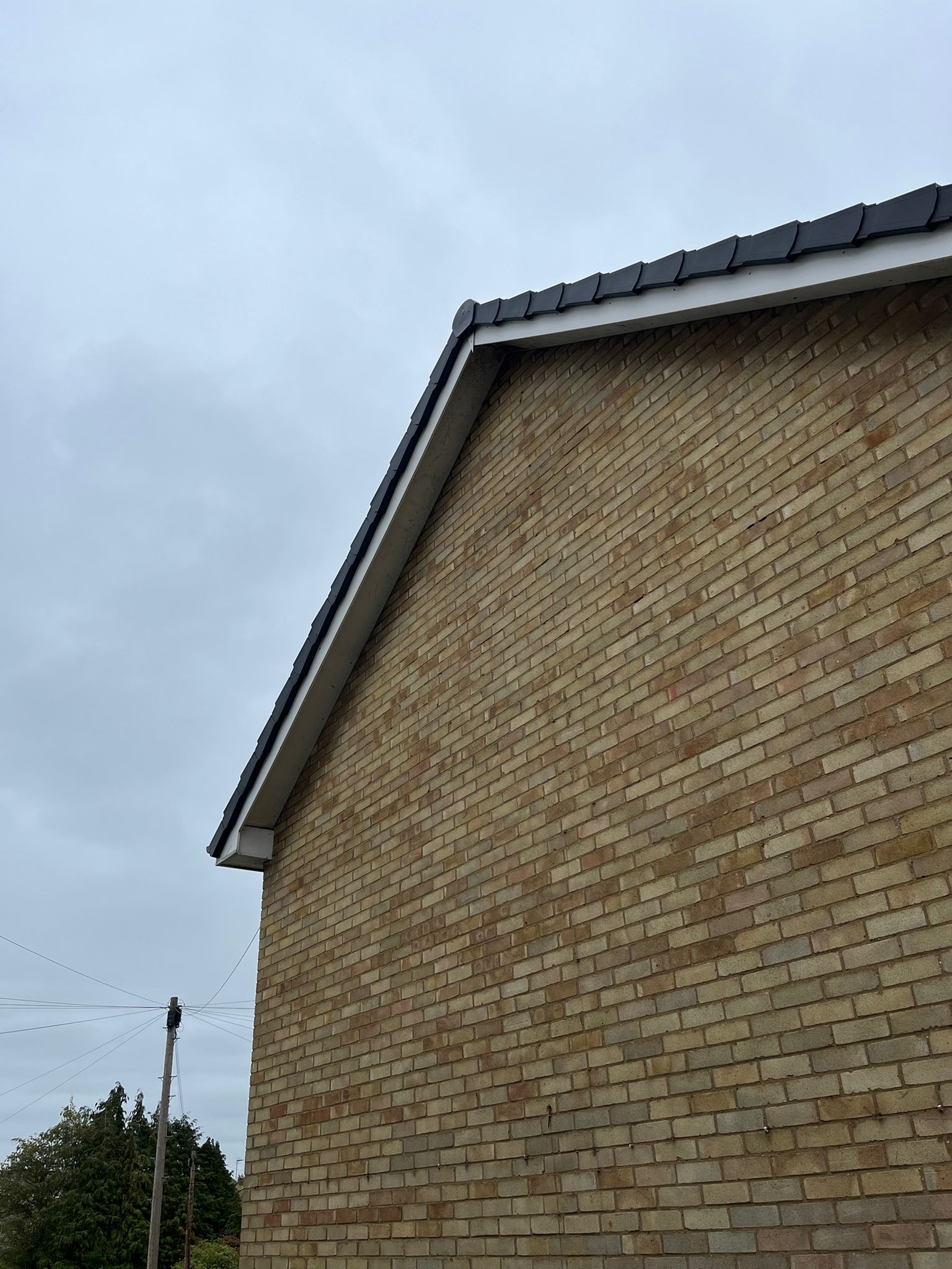 A newly finished gable roof by Belstead Roofing, with grey ridge tiles and fresh white fascia and guttering